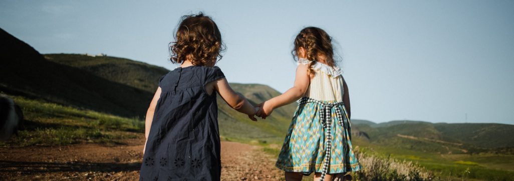 2 girls in blue dress standing on brown field during daytime